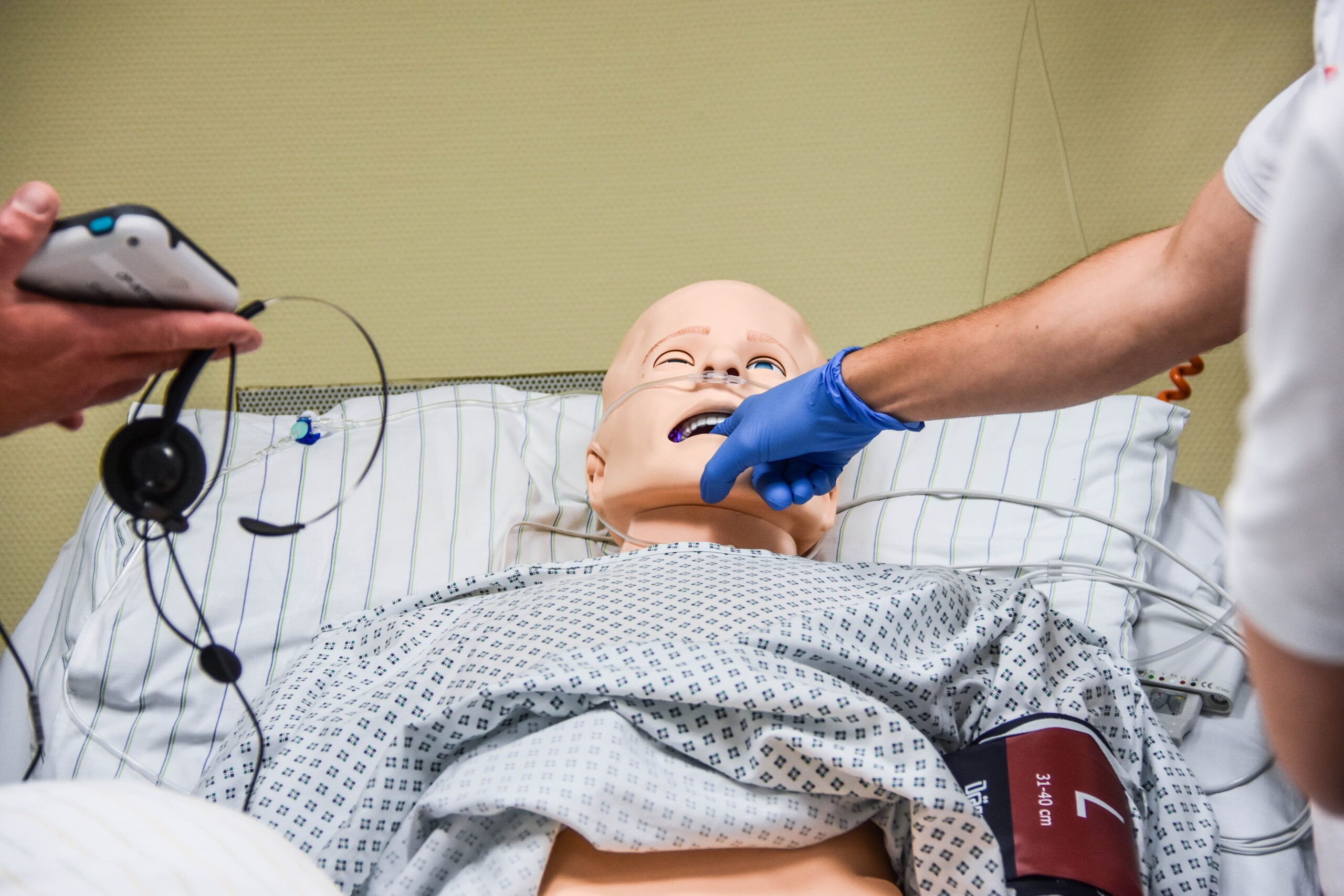 Eine medizinische Puppe eines erwachsenen Menschen liegt verkabelt im Krankenhausbett